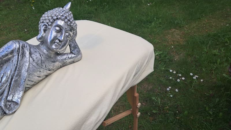Ruhende Buddha-Figur auf einer Massageliege im Garten
